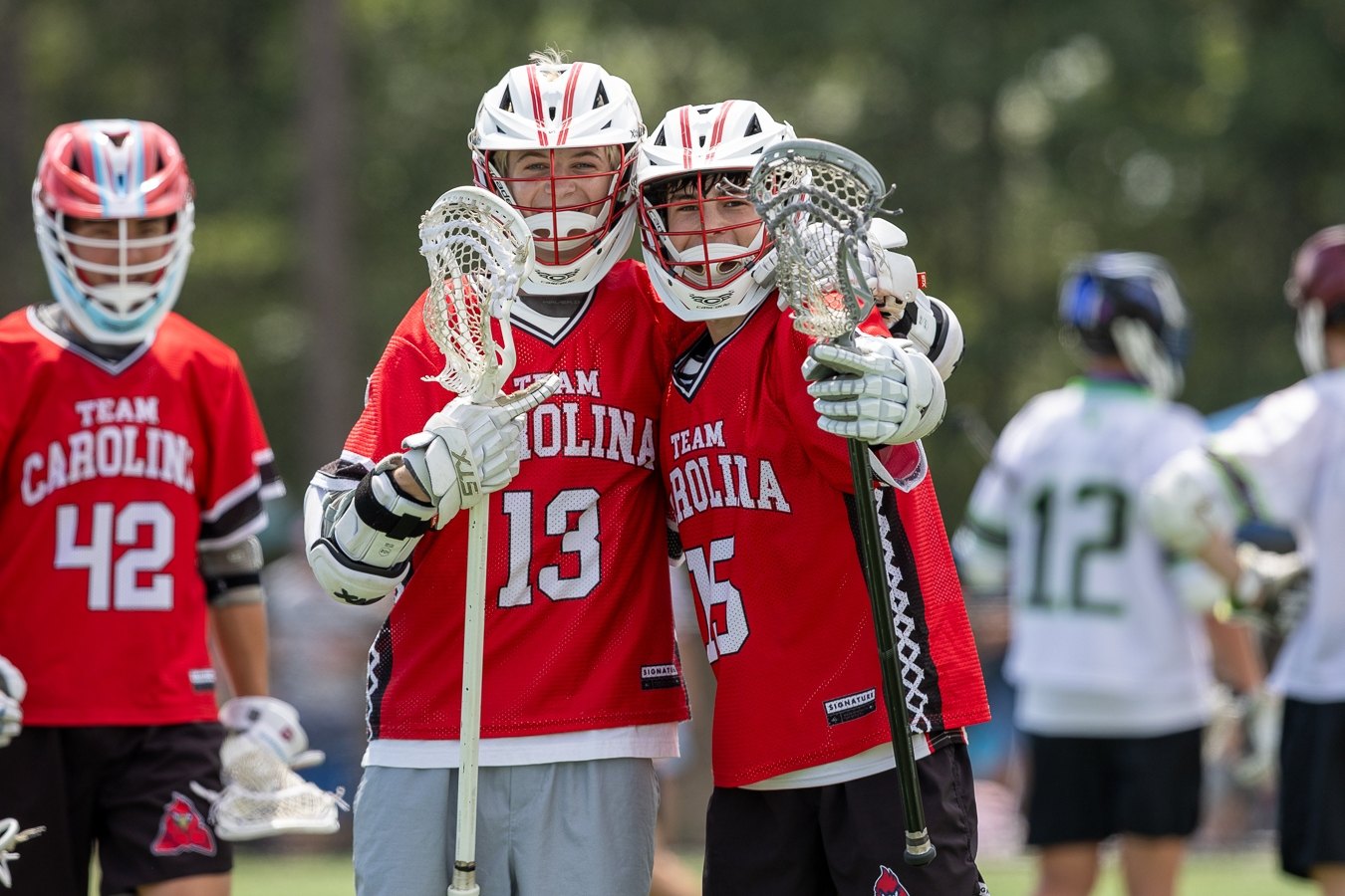 Team Carolina teammates in red jerseys posing together on the field after a tournament game
